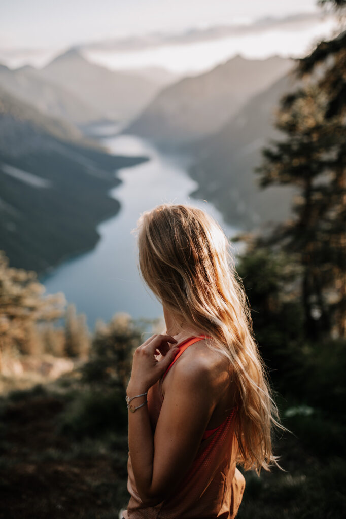 Blonde Frau mit langen Haaren auf einem Berggipfel über dem Plansee in Tirol